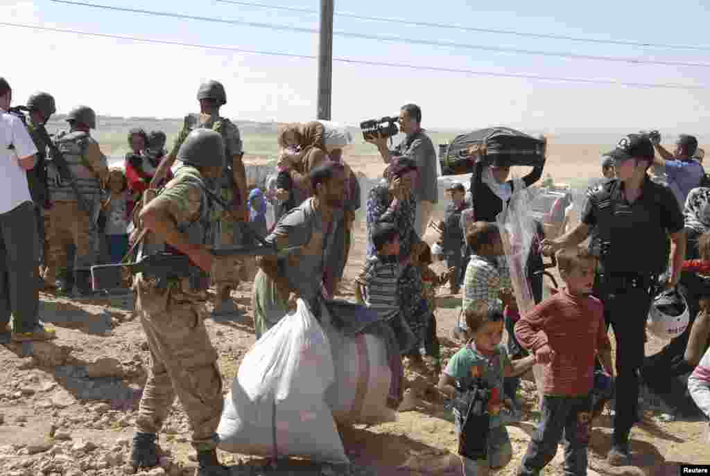 Syrian Kurds cross the border fence into Turkey near the southeastern town of Suruc in Sanliurfa province, September 19, 2014. Several thousand Syrian Kurds began crossing into Turkey on Friday fleeing Islamic State fighters who advanced into their villag
