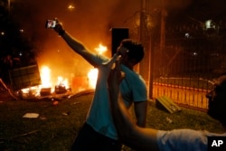 FILE - Two men pose for selfies during a protest against presidential re-elections at Congress in Asuncion, Paraguay, March 31, 2017.