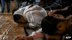 FILE— Christian worshippers kneel at the Unction Stone, believed to be the place where Christ's body was laid down after being removed from the crucifix and prepared for burial, at the Church of the Holy Sepulchre in the Old City of Jerusalem, on Good Friday on March 29, 2024.