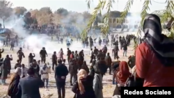 Iranian security forces appear to fire tear gas at anti-government protesters on the dry bed of the Zayandehrud River in Isfahan in this screen grab of a video posted to social media on Nov. 26, 2021. Isfahan's centuries-old Khajoo bridge can be seen at the upper right.