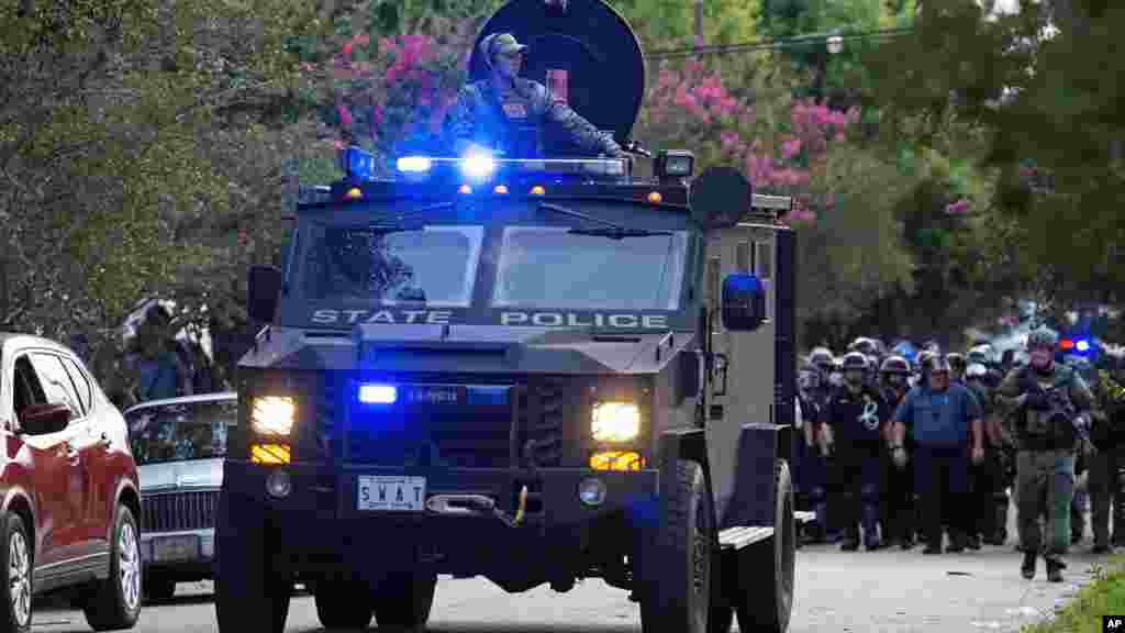 Un camion blindé de la police roule en tête d'une patrouille de policiers dans un quartier résidentiel à Baton Rouge.