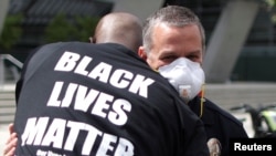 Un manifestante vestido con una camiseta con el lema 'Black Lives Matter' (Las vidas negras importan) abraza a un agente de la policía durante un protesta en la ciudad de Los Ángeles, el 2 de junio.