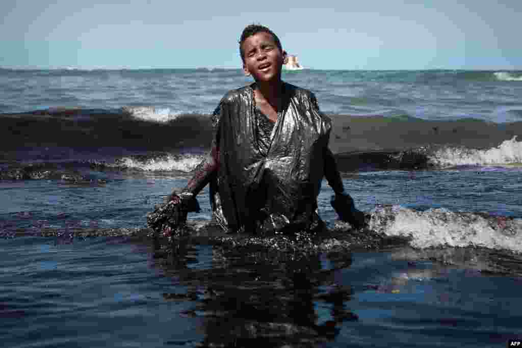 A boy covered in oil from a spill, walks out of the sea on Itapuama beach in the city of Cabo de Santo Agostinho, Pernambuco state, Brazil, Oct. 21, 2019.