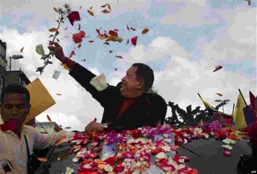 Venezuela's President Hugo Chavez catches a flower thrown by supporters during his caravan from Miraflores presidential palace to the airport in Caracas, Venezuela, Friday Feb. 24, 2012. Chavez bid an emotional goodbye to soldiers and supporters and waved