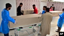 Hospital staff gather beside the bodies of persons who were killed by gunmen, at a hospital morgue in Quetta, Pakistan, on April 13, 2024.