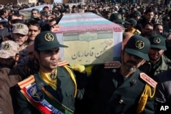 FILE - Civilians and armed forces members carry the flag-draped coffins of Iranian Revolutionary Guard Gen. Mohsen Ghajarian, foreground, and five soldiers who were killed in fighting in Syria, during their funeral outside the headquarters of the guard's ground forces, in Tehran, Iran, Feb. 6, 2016.