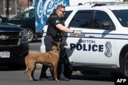 Un oficial de policía y su perro regresan a su vehículo después de revisar los terrenos del Ayuntamiento de Springfield en busca de explosivos tras amenazas de bomba en edificios en Springfield, Ohio, el 12 de septiembre de 2024.