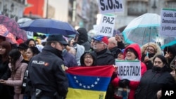 Una mujer sostiene una bandera venezolana mientras otros abarrotan la Puerta del Sol esperando a Juan Guaidó durante su visita a Madrid, España. Enero 25, 2020.