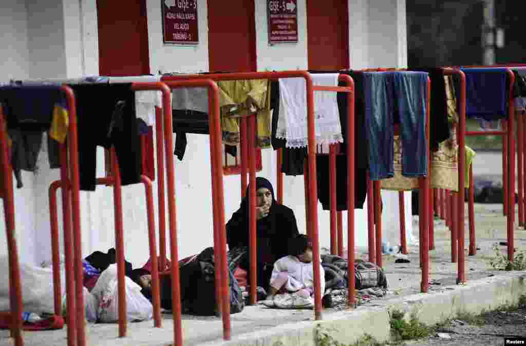 A Syrian migrant woman sits with a baby outside the Sarayici oil wrestling arena in Edirne, Turkey, as they wait to be allowed to continue their journey to Europe.