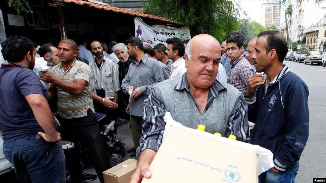 Người tị nạn Syria nhận thực phẩm của Chương trình Lương thực Thế giới phân phối tại một trung tâm ở Damascus