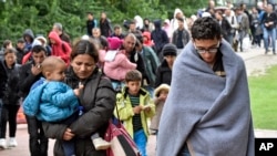 Migrants walk from the main station in Dortmund, Germany, to a hall where they get first attendance, Sept. 6, 2015.