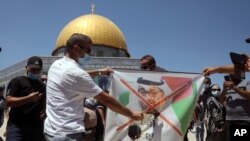Palestinian protesters burn a banner showing Abu Dhabi Crown Prince Mohamed bin Zayed al-Nahyan during a protest against the United Arab Emirates' deal with Israel near the Dome of the Rock Mosque in the Al Aqsa Mosque compound in Jerusalem's old city.