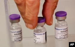 A health worker takes a dose of the Pfizer-BioNTech COVID-19 vaccine at the Rene-Muret hospital in Servan near Paris, Dec. 27, 2020.