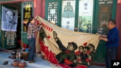 资料照片：在文革爆发30周年之际，北京一处古玩市场的商贩们展开一面1969年的横幅，显示毛泽东“视察无产阶级文化大革命大军”以及“大海航行靠舵手”口号。(2016年5月16日)