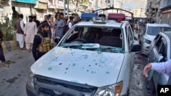 Police officers examine a damaged police vehicle at the site of bomb blast, in Quetta, Pakistan, Monday, April 10, 2023.