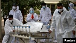 Petugas menarik tandu yang membawa korban yang meninggal karena COVID-19 ke kamar mayat di Ahmedabad, India, 8 Mei 2021. (REUTERS / Amit Dave)