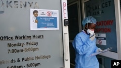 FILE -Llaboratory technician Irene Ooko walks outside to take a nasal sample from a patient seeking a test for the new coronavirus that causes COVID-19, at the Pathologists Lancet Kenya laboratory in Nairobi, Kenya.