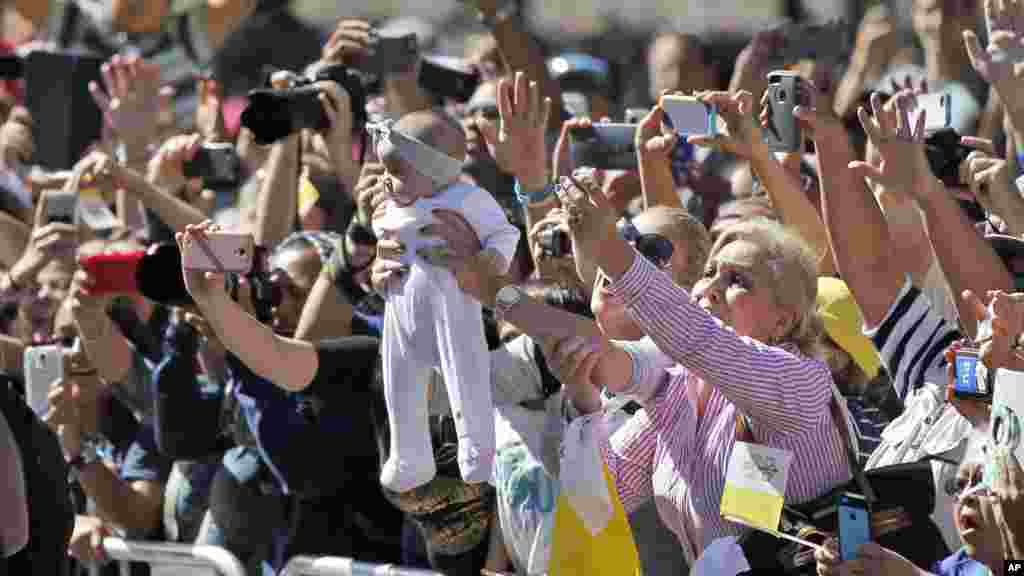 Un bébé est soulevé dans la foule au passage de la papamobile lors de la parade papale à Washington, 23 septembre 2015.