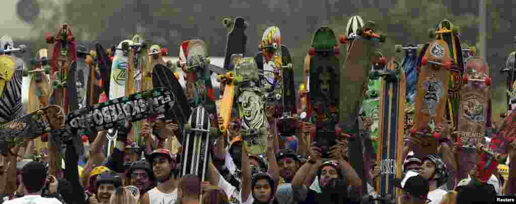 Skateboarders raise their skateboards as they line up at the starting line of the Skate Run competition in Sao Paulo, Brazil, Sept. 22, 2013.