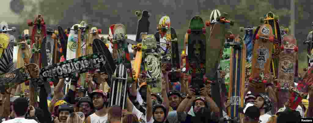 Para pemain skateboard mengangkat papan skate mereka ketika berbaris di garis START untuk mengikuti lomba di kota Sao Paulo, Brazil.