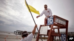 Tybee Island Ocean Rescue Senior Lifeguard Todd Horne, right, and Mark Eichenlaub, left, hang a yellow flag that warns swimmer of strong rip currents from Hurricane Arthur along the beach, on Tybee Island, Georgia, July 3, 2014. 