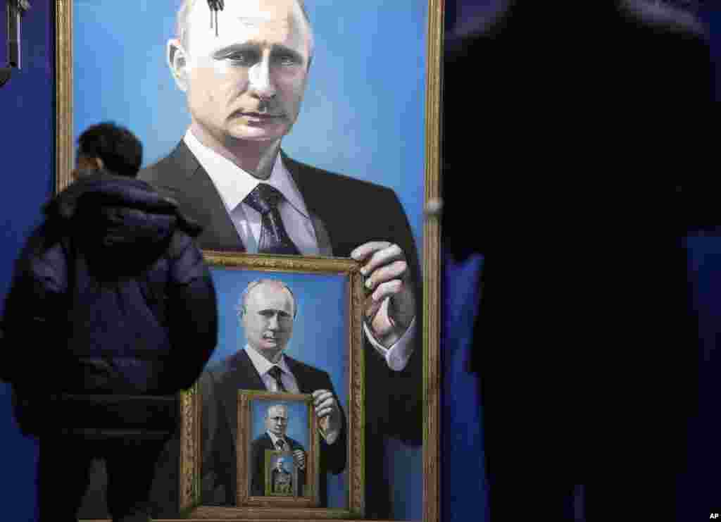 Visitors look at paintings of Russian president Vladimir Putin at the "SUPERPUTIN" exhibition at the UMAM museum in Moscow, Russia.