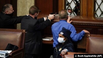 FILE - Police with guns drawn watch as protesters try to break into the House Chamber at the U.S. Capitol on Wednesday, Jan. 6, 2021, in Washington. (AP Photo/J. Scott Applewhite)