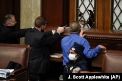 Police with guns drawn watch as protesters try to break into the House Chamber at the U.S. Capitol on Wednesday, Jan. 6, 2021, in Washington. (AP Photo/J. Scott Applewhite)