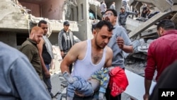 EDITORS NOTE: Graphic content / TOPSHOT - Um homem carrega o corpo de uma criança que foi resgatada dos escombros após os bombardeamentos israelitas na casa de quatro andares da família Muqat, no bairro de Zarqa, no norte da cidade de Gaza, em 26 de outubro de 2024