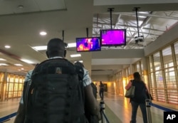 FILE - Passengers from an Ethiopian Airlines flight from Addis Ababa walk past a thermal imaging camera checking for signs of fever upon their arrival at the Jomo Kenyatta International Airport in Nairobi, Kenya, Feb. 6, 2020.