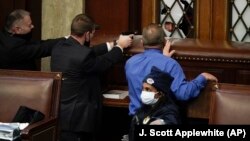 FILE - Police with guns drawn watch as protesters try to break into the House Chamber at the U.S. Capitol on Wednesday, Jan. 6, 2021, in Washington. (AP Photo/J. Scott Applewhite)