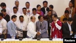 Myanmar President Thein Sein (front 3rd L) and Naing Han Tha (front 3rd R), a leader of the Nationwide Ceasefire Coordinating Team (NCCT), shake hands after signing a nationwide ceasefire draft agreement at the Myanmar Peace Center in Yangon, March 31, 2015.
