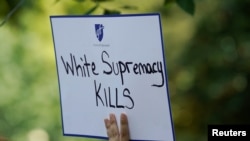 Seorang perempuan membawa poster bertuliskan "Supremasi Kulit Putih Membunuh" dalam aksi protes di depan Gedung Putih, Washington, pada 6 Agustus 2019. (Foto: Reuters/Kevin Lamarque)