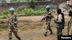 U.N. peacekeepers walk past rebel soldiers in Bunagana, July 7, 2012. 