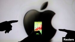 Men are silhouetted against a video screen with an Apple Inc logo as they pose with a Samsung Galaxy S3 smartphone, May 17, 2013.