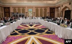 FILE - A handout photo released by Qatar's Ministry of Foreign Affairs on Feb. 26, 2019, shows Qatari officials, center, taking part in a meeting between U.S. officials, left, and members of the Taliban delegation in Doha.