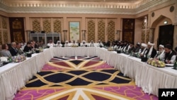 FILE - A handout photo released by the official Qatar's Ministry of Foreign Affairs on Feb. 26, 2019, shows Qatari officials, center, taking part in meeting between the U.S. delegation, left, and the Taliban delegation in Doha. 