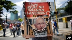 Anti-government demonstrators holds a poster that reads in Spanish "The jails won't shut the truth" and the image of opposition leader arrested Antonio Ledezma during a protest against Venezuela's President Nicolas Maduro in Caracas, Venezuela, Aug. 12, 2017.