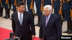 Chinese President Xi Jinping, left, acknowledges Palestinian President Mahmoud Abbas as they walk together during a welcome ceremony at the Great Hall of the People in Beijing, July 18, 2017.