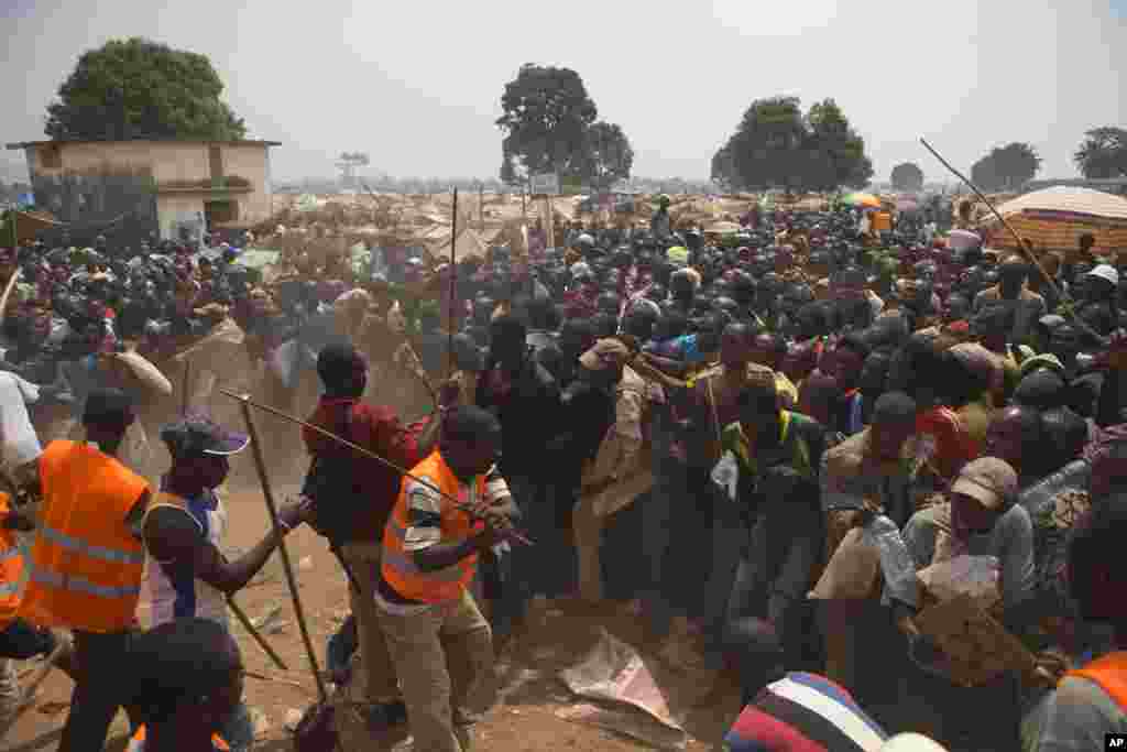 Security volunteers use sticks to fend off the crowd trying to enter a food and supplies distribution point at a makeshift camp at Mpoko Airport, in Bangui, Jan. 9, 2014. 