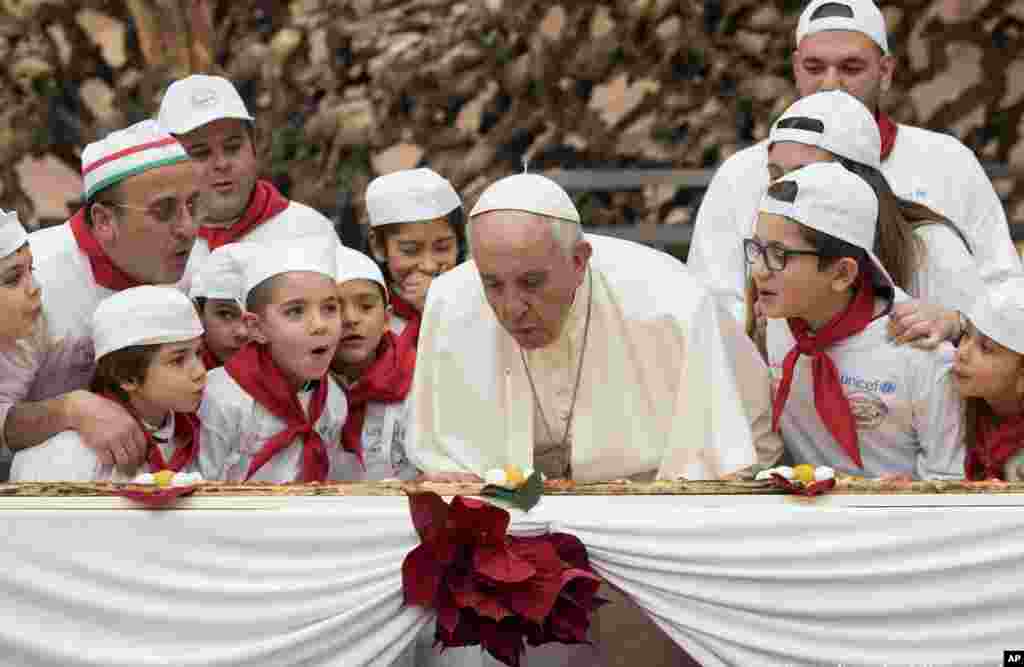 Pope Francis blows a candle on the occasion of his 81st birthday during a private audience with children the Paul VI hall at the Vatican.