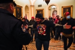 Protesters gesture to U.S. Capitol Police in the hallway outside of the Senate chamber at the Capitol in Washington, Jan. 6, 2021, near the Ohio Clock.