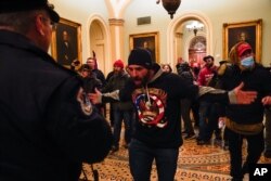 Protesters gesture to U.S. Capitol Police in the hallway outside of the Senate chamber at the Capitol in Washington, Jan. 6, 2021, near the Ohio Clock.
