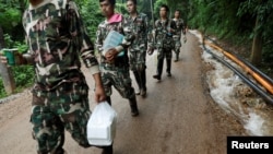 Para petugas penyelamat membawa bantuan di dekat komplek gua Tham Luang, di Provinsi Chiang Rai, di utara Thailand, 4 Juli 2018. 