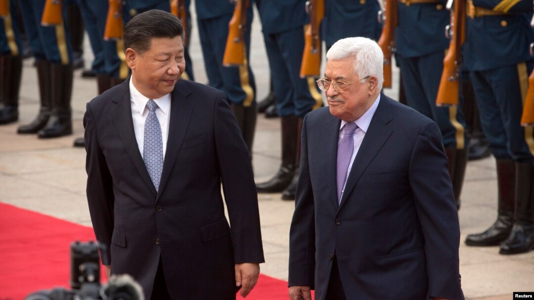 Chinese President Xi Jinping, left, acknowledges Palestinian President Mahmoud Abbas as they walk together during a welcome ceremony at the Great Hall of the People in Beijing, July 18, 2017.