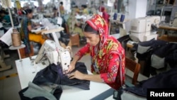 FILE - A worker is seen in a garment factory in Savar, Bangladesh. Two mobile services, both by U.S.-based companies, encourage workers to call toll-free numbers to anonymously log violations they see around them.