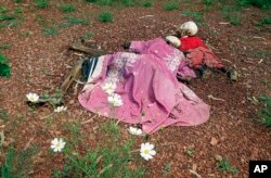 FILE - The bodies of a woman and her child lie by a church in Nyarubuye, Rwanda, on May 31, 1994. The village was the site of an April 14 massacre that was part of Rwanda's genocide in which 800,000 people were killed.