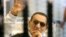 Former Egyptian President Hosni Mubarak waves to his supporters from behind bars as he attends a hearing in his retrial on appeal in Cairo, April 13, 2013.