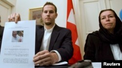 FILE - Christine Levinson (right), wife of former FBI agent Robert Levinson, watches as her son Daniel Levinson displays a web print of his father's picture to journalists while attending a news conference at Switzerland's embassy in Tehran, Dec. 22, 2007