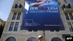 An Israeli youth walks past a poster welcoming and supporting US President Donald Trump in downtown Jerusalem, on May 19, 2017.